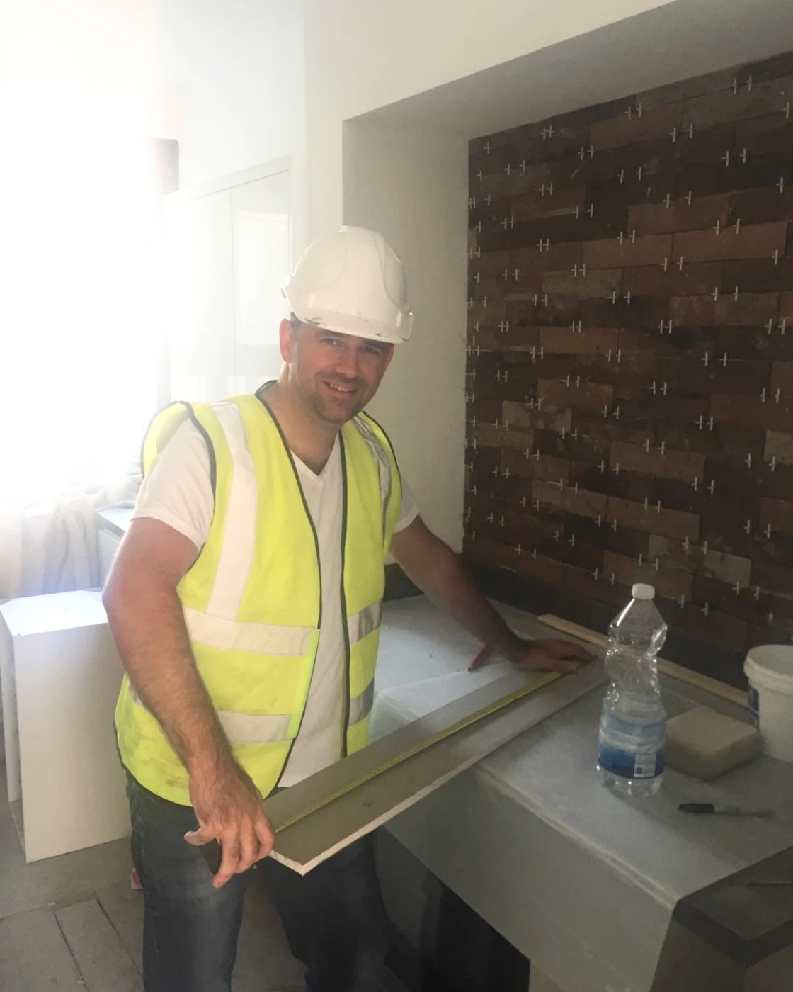 Paul in a hard hat and hi-vis, fitting out a kitchen on one of his own refurbs